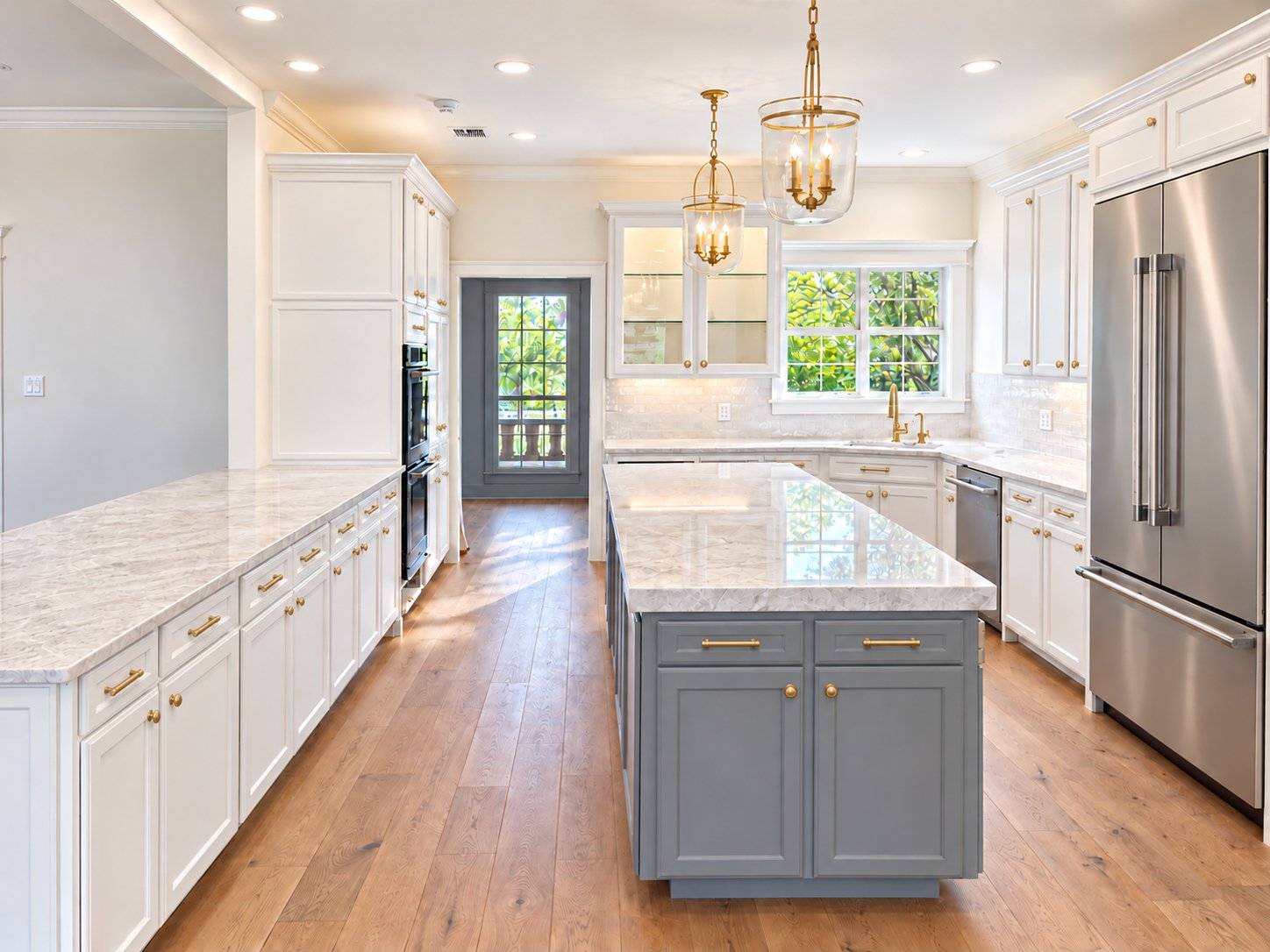 Kitchen with grey island, marble counters and brass lanterns, looking toward the back door