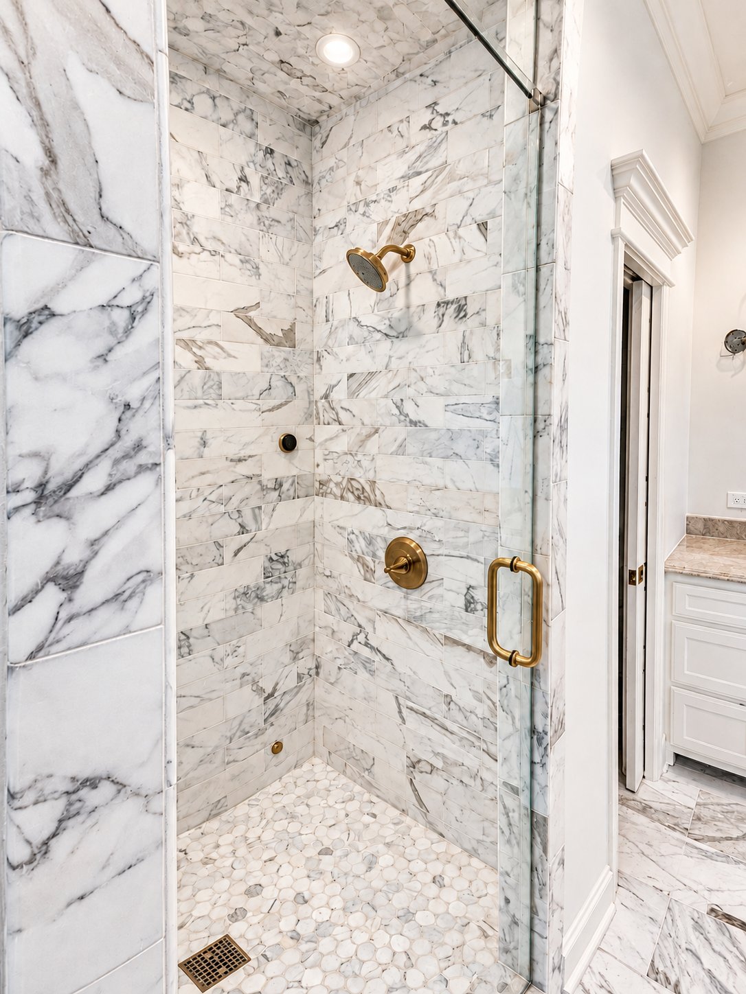Marble shower of the Traditional home renovation by Kreifels Construction, with brass fixtures